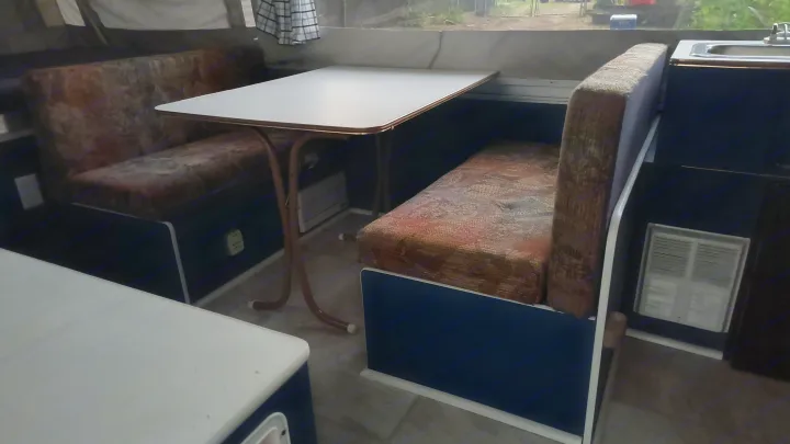 RV rental camper: Cozy dinette with patterned benches & white table. Sink visible, ready for your road trip.. Coleman Destiny Santa Fe 1996