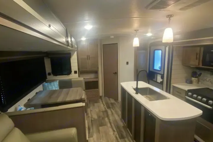 Spacious RV rental interior with a modern kitchen island, dining booth, and ample storage. Perfect for your next adventure.. Crossroads RV Sunset Trail Super Lite 2023