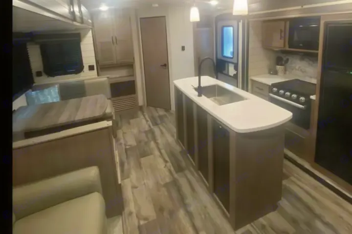 Modern RV rental interior: a full kitchen with island sink, dining area, and comfortable living space. Ideal travel trailer.. Crossroads RV Sunset Trail Super Lite 2023