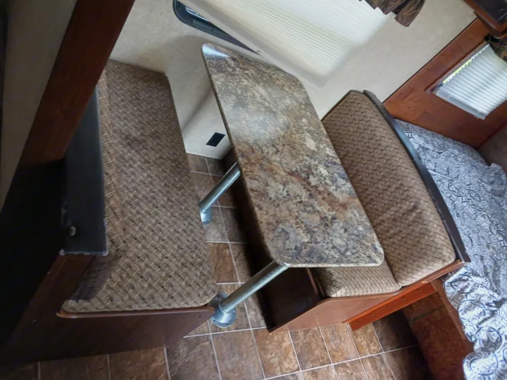 RV rental interior: Dinette with patterned benches, a mottled table, and a glimpse of the bed and window.. Keystone RV Hideout LHS 2015