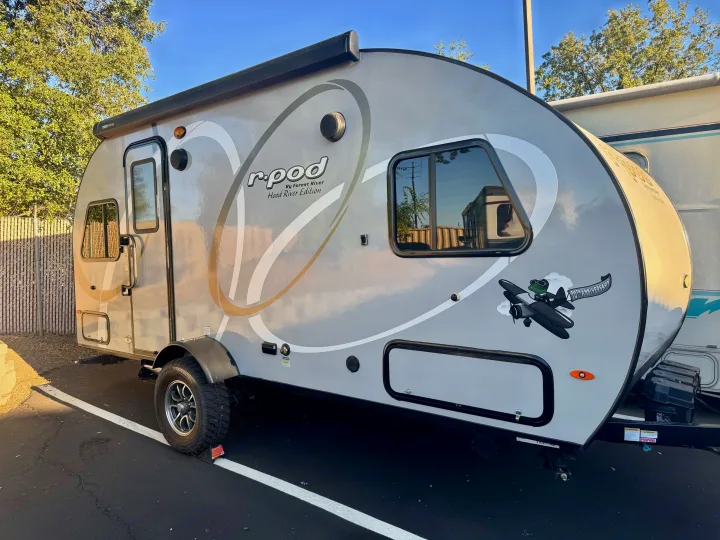 This r-pod travel trailer, a sleek RV rental, is ready for your next outdoor adventure, parked on asphalt with sun shining.. Forest River RPod 189 2019
