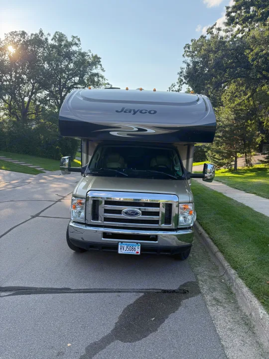 Front view of a beige Jayco RV rental, a recreational vehicle on a Ford chassis, parked on a sunny street.. Jayco Greyhawk 2018