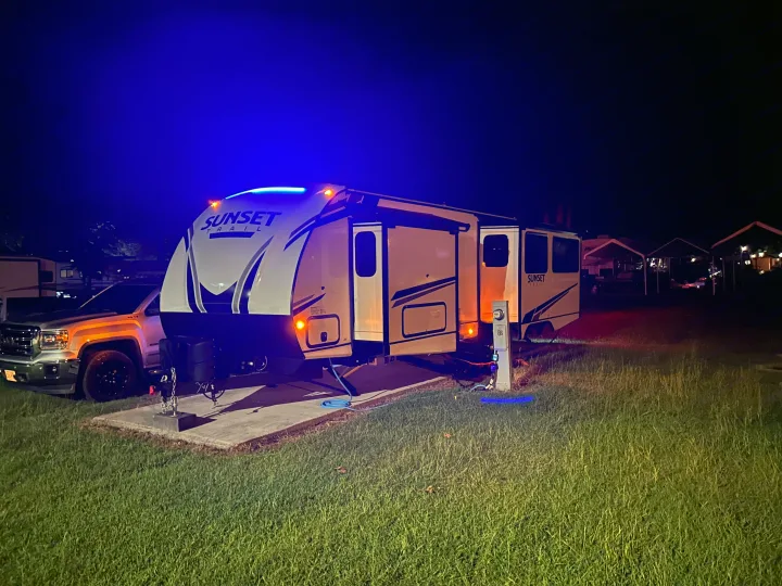 Night camping with this illuminated Sunset Trail rv rental, complete with hookups and tow vehicle at a cozy campsite.. Crossroads RV Sunset Trail 2022