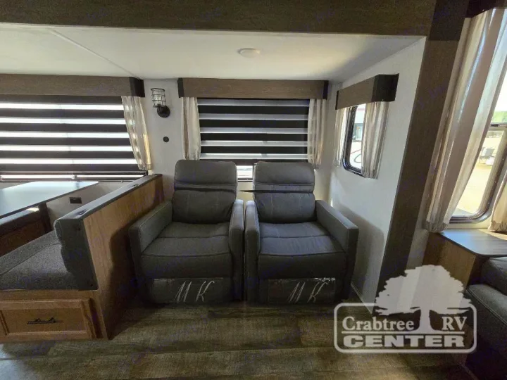 Spacious RV rental living area featuring two gray recliners and a dinette setup. Ideal for travel comfort.. Forest River Cherokee M-274WK 2024