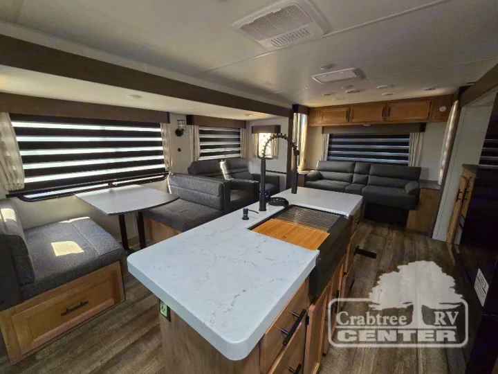 Explore this modern RV rental's cozy interior, featuring a kitchen island, dinette, and sofa lounge.. Forest River Cherokee M-274WK 2024