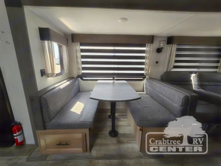 Compact RV rental interior featuring a cozy dinette with gray seating and windows, ideal for meals & relaxation on the go.. Forest River Cherokee M-274WK 2024