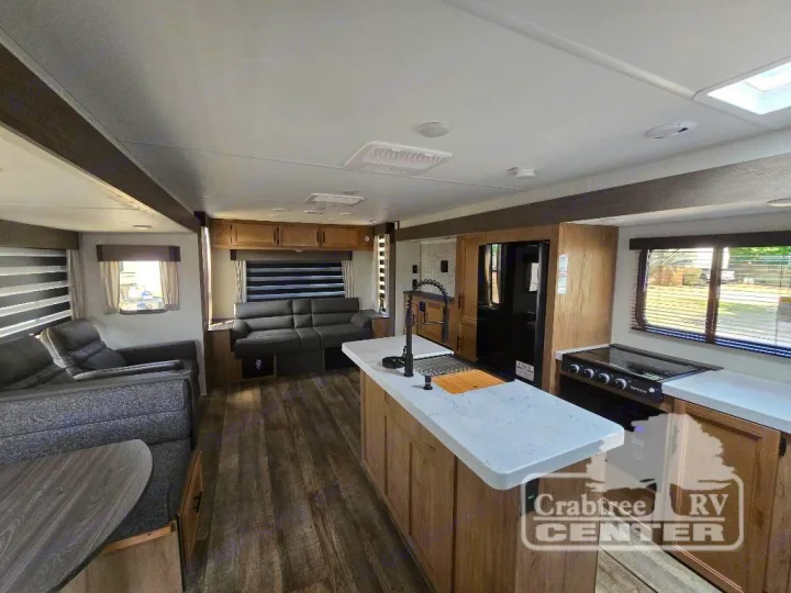Spacious, modern RV rental interior with kitchen island, stove, fridge, and comfortable living area featuring sofas and windows.. Forest River Cherokee M-274WK 2024