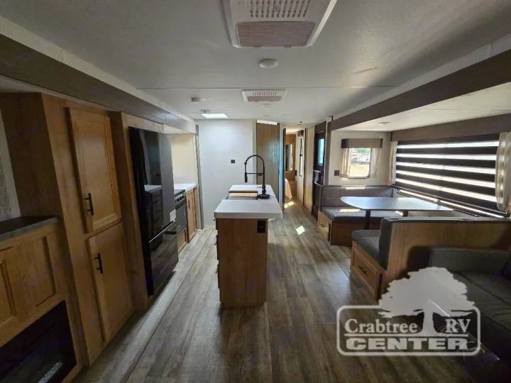 Spacious RV rental interior featuring a modern kitchen island, dining booth, and comfortable living area.. Forest River Cherokee M-274WK 2024