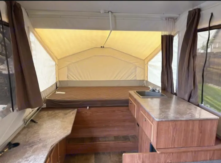 RV rental: Inside a pop-up camper, with a bed, a kitchen sink on a speckled counter, and wood-toned floors.. Rock wood 1940 LTD 2016