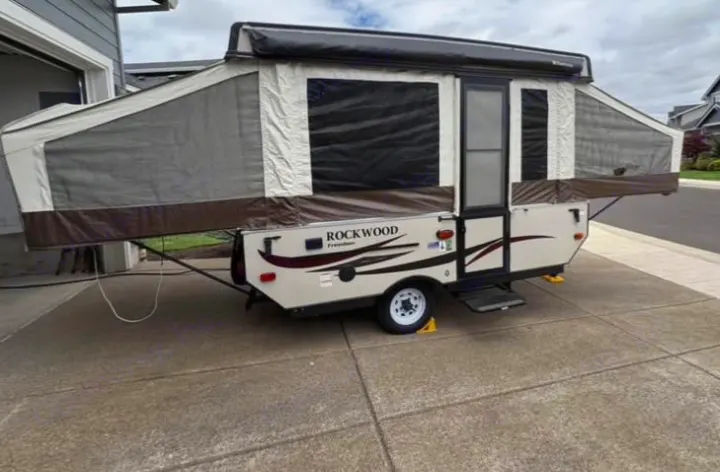A Rockwood pop-up camper, fully set up on a driveway, showcasing its extended canvas and screened windows. Great for RV rental.. Rock wood 1940 LTD 2016
