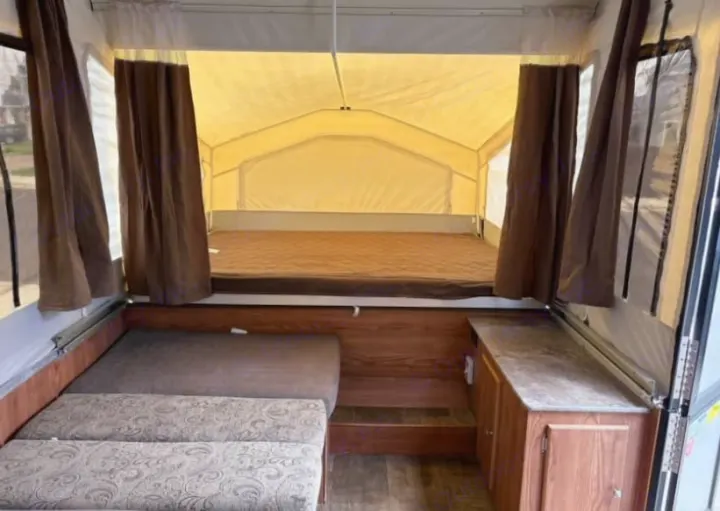 Interior of an RV rental: cozy pop-up camper with a bed, seating, and counter space. Perfect for travel.. Rock wood 1940 LTD 2016