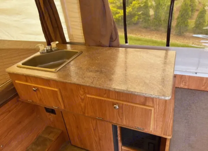 RV rental: Pop-up camper's interior kitchen, featuring a sink, wooden cabinets, and a scenic outdoor view.. Rock wood 1940 LTD 2016