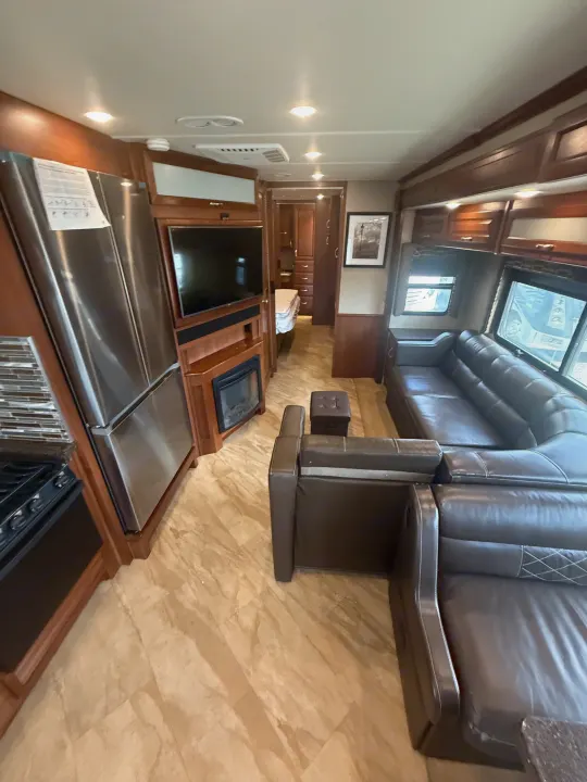 RV rental interior: living area with leather sofas, TV, fireplace, kitchen, and bedroom access. Modern, comfortable setup.. Fleetwood Bounder 2016