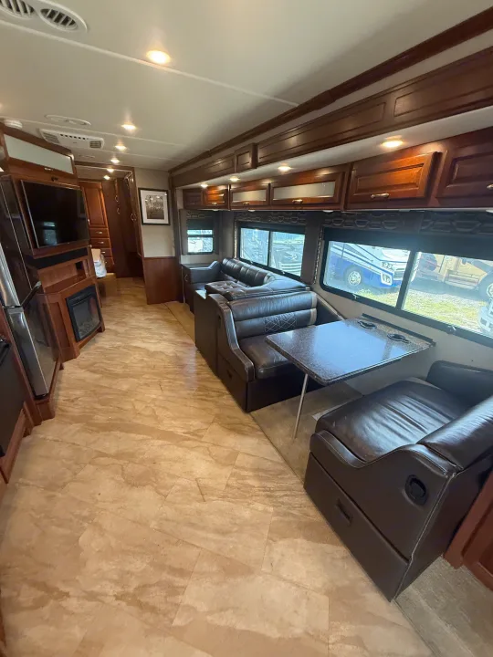 Spacious RV rental interior with a comfortable leather sofa, dinette, kitchen appliances, and fireplace, perfect for travel.. Fleetwood Bounder 2016