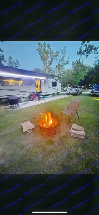 Enjoying a peaceful night at a scenic RV rental campsite, featuring a glowing campfire & illuminated travel trailer.. Crossroads RV Sunset Trail 2022