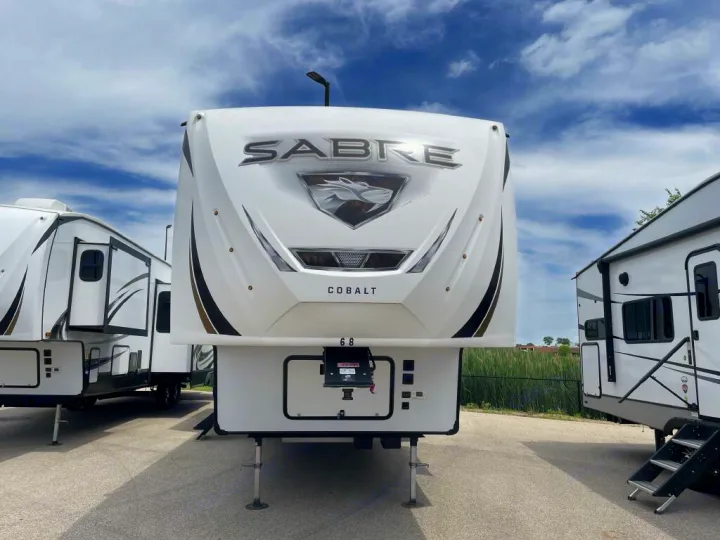 Front view of a white Sabre Cobalt fifth-wheel RV, ideal for an RV rental adventure. Parked under a cloudy sky.. Forest River Sabre 2021