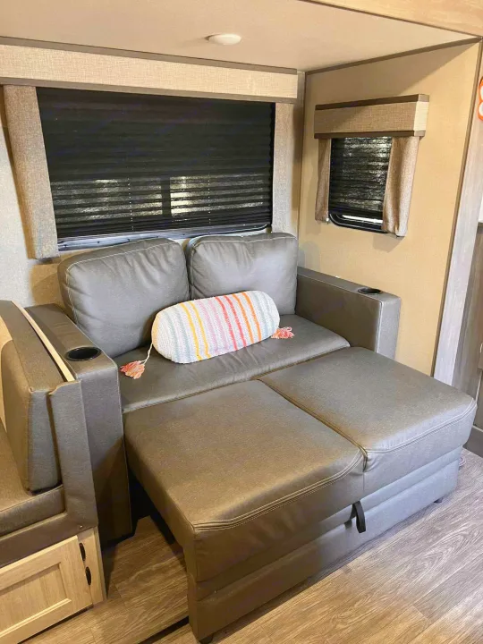 Comfortable RV rental sofa converts to a bed or lounge, featuring cup holders and modern design for easy living.. Forest River Aurora Aurora 2024