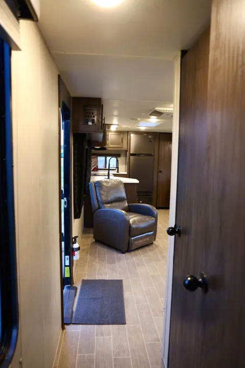 Experience comfort in this RV rental interior, featuring a cozy recliner, full kitchen, and modern finishes for your travels.. Forest River Cherokee 2020