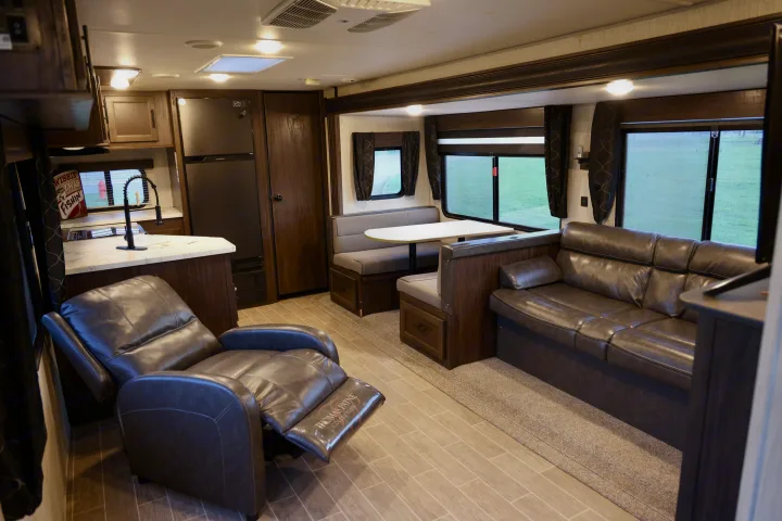 Spacious RV rental interior featuring a modern living area with a leather recliner, sofa, dinette, and a full kitchen.. Forest River Cherokee 2020