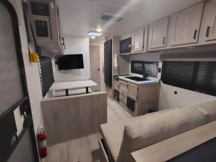 Spacious RV rental interior with kitchen, dinette, sofa, and overhead storage. Ideal for a comfortable camper experience.. East to West Della Terra LE 2024