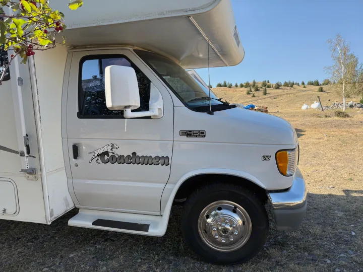 White Coachmen E-450 Super Duty RV rental with Triton V10 engine, parked on dry land. Great for camping & road trips.. Coachmen Leprechaun 2002