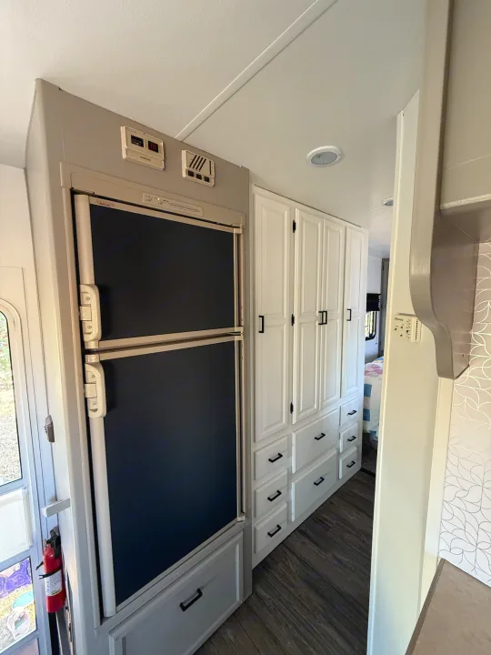 RV rental interior featuring a two-door fridge, extensive white cabinets, and sleek flooring, offering ample storage for travel.. Coachmen Leprechaun 2002