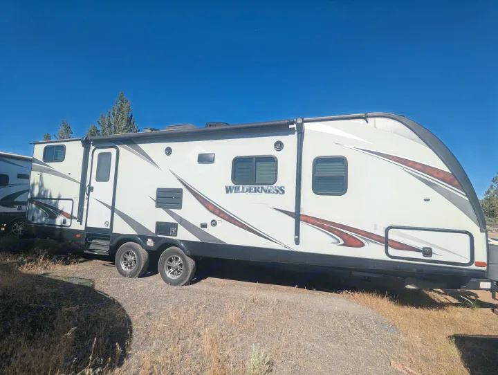 Wilderness travel trailer RV rental parked outdoors under a blue sky, ready for adventure.. Heartland RVs Wilderness 2018