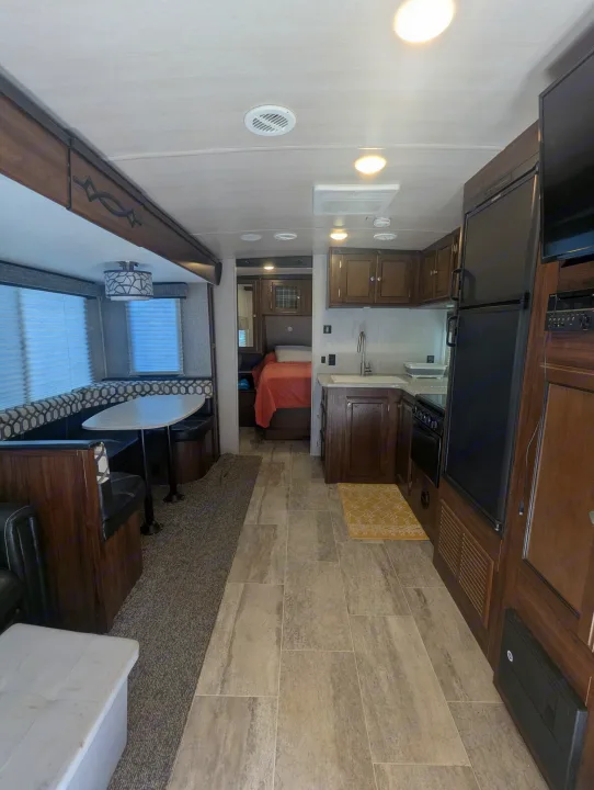 Spacious RV rental interior: dinette, kitchen, and bedroom visible. Features light tile and carpet flooring.. Heartland RVs Wilderness 2018