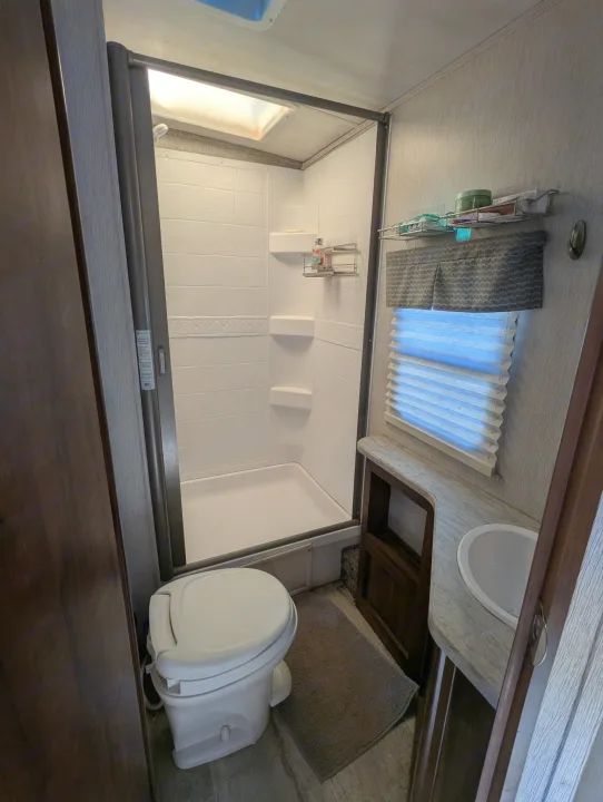Full view of a clean, compact RV rental bathroom, showcasing the shower, toilet, and sink.. Heartland RVs Wilderness 2018