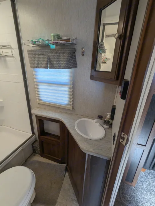 Compact RV rental bathroom with shower, toilet, and sink. Includes wall shelving & mirror for travelers.. Heartland RVs Wilderness 2018