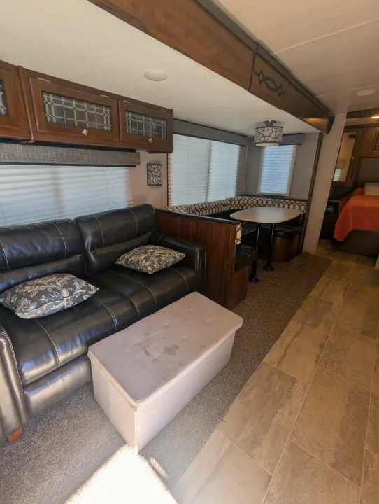 Spacious RV rental interior with a comfy black leather sofa, dining area, and bedroom. Ready for your adventure!. Heartland RVs Wilderness 2018