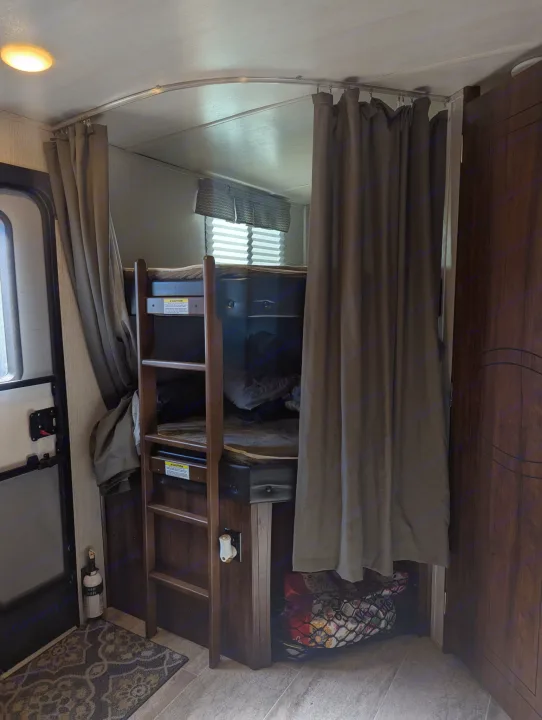 RV rental: Inside a camper, private bunk beds with curtains, a ladder, and under-bed storage, plus a safety extinguisher.. Heartland RVs Wilderness 2018