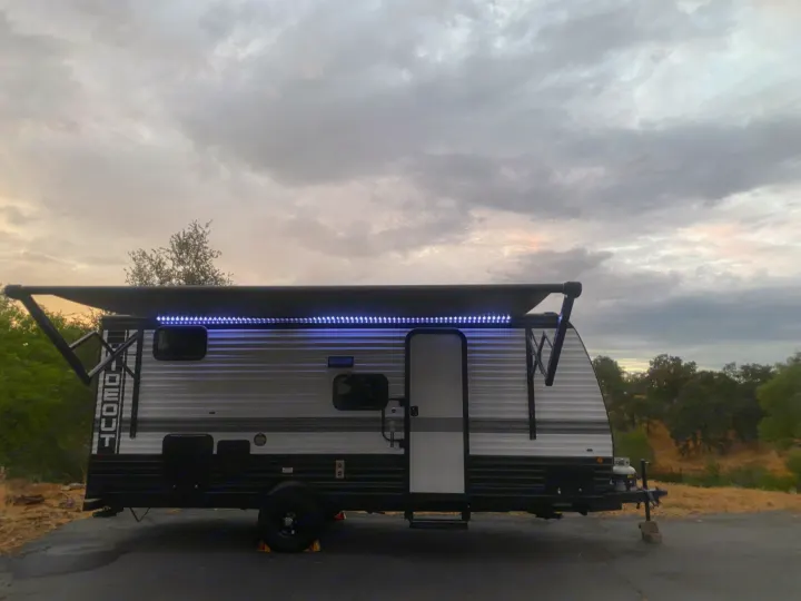 Ready for adventure! This RV rental with LED awning lights is perfect for a camping trip under cloudy skies.. Keystone RV Hideout Sport 2024