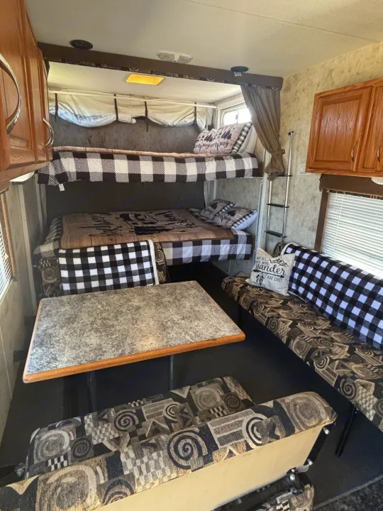 RV rental interior features bunk beds with black and white buffalo check bedding, a dining table, and patterned benches.. Eclipse Recreational Vehicles Attitude 2006