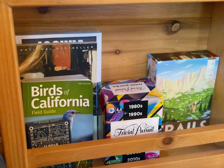 RV rental fun: Shelf of leisure with "Birds of California" guide, Trivial Pursuit games, and more for travel entertainment.. RAM Promaster 2500 2020