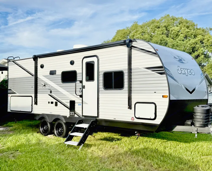 A modern Jayco travel trailer for RV rental, parked on green grass under a blue sky, showing its exterior.. jayco 235MBH Jay Flight TT 2025