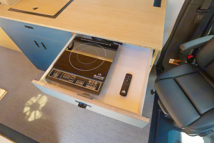 Inside an rv rental: a clever pull-out drawer reveals a Duxtop induction cooktop & remote, perfect for compact kitchen use.. Geotrek Flatiron Summit 2025