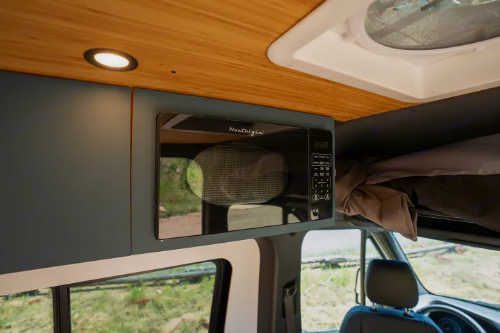 RV rental interior: handy overhead microwave, sleek cabinetry, and lighting for your journey.. Geotrek Flatiron Summit 2025