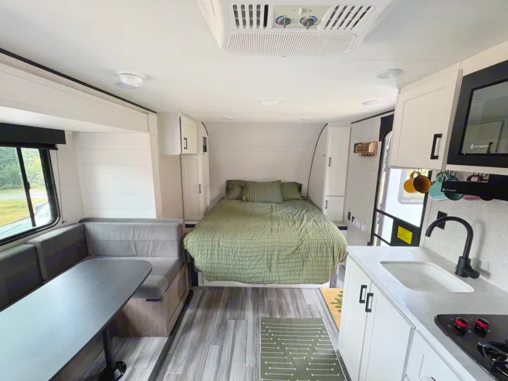 Modern RV rental interior showing a comfortable bed, dining area, and kitchen. Perfect for your next adventure.. Jayco Jay Flight 197MB 2025