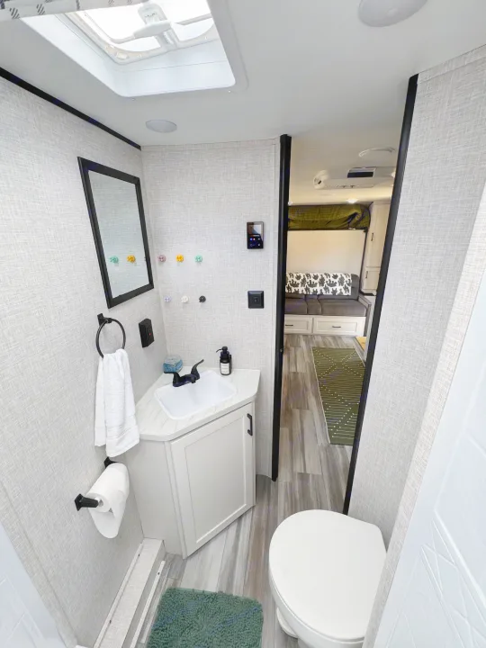 Modern RV rental bathroom with sink, toilet, and view into the cozy living area. Ideal for travel comfort.. Jayco Jay Flight 197MB 2025