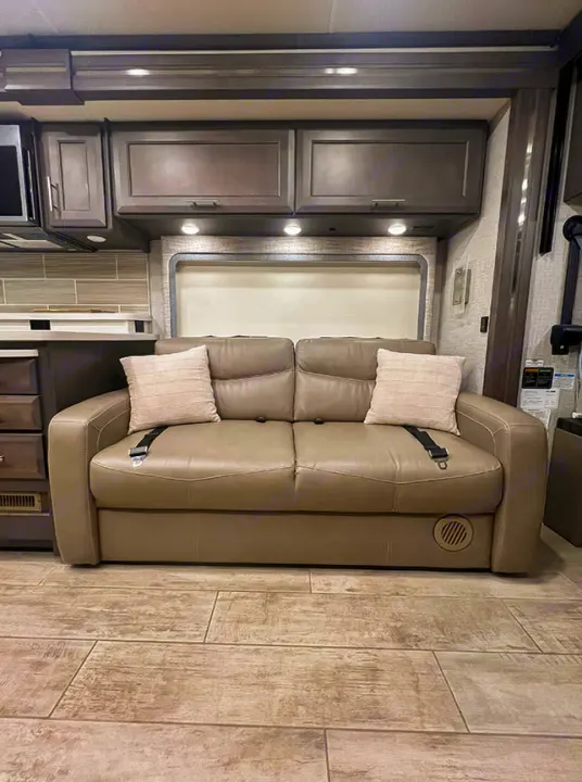 RV rental: Modern interior featuring a comfy tan sofa with seatbelts, dark wood cabinetry, and wood-look tile flooring.. Thor Motor Coach 2023