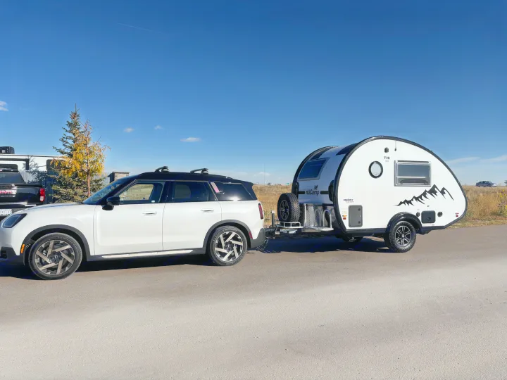 A white MINI Countryman towing a nüCamp T@B teardrop RV rental on a clear day. Perfect setup for outdoor travel.. nuCamp T@B 2024