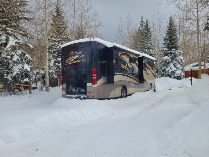 Large Berkshire rv rental amidst snow-covered trees. Parked with slide-outs extended, ready for winter camping.. Forest River Berkshire 390-Bunkhouse 2012