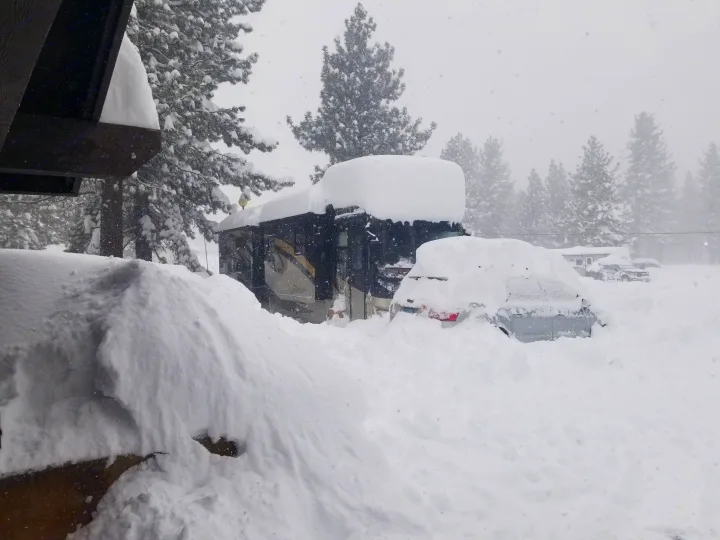 Deep snow buries an RV rental and car during a harsh winter storm, highlighting severe travel conditions.. Forest River Berkshire 390-Bunkhouse 2012