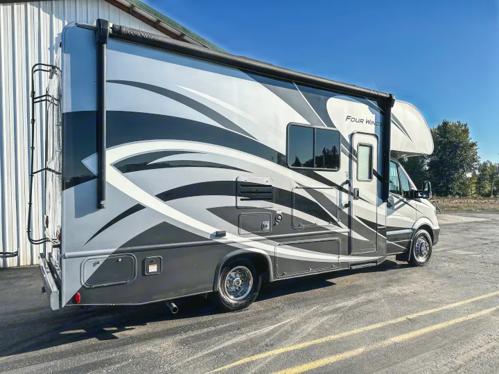 Grey & black RV rental: A "Four Winds" recreational vehicle, parked outdoors on a sunny day.. Thor Four Winds 2019
