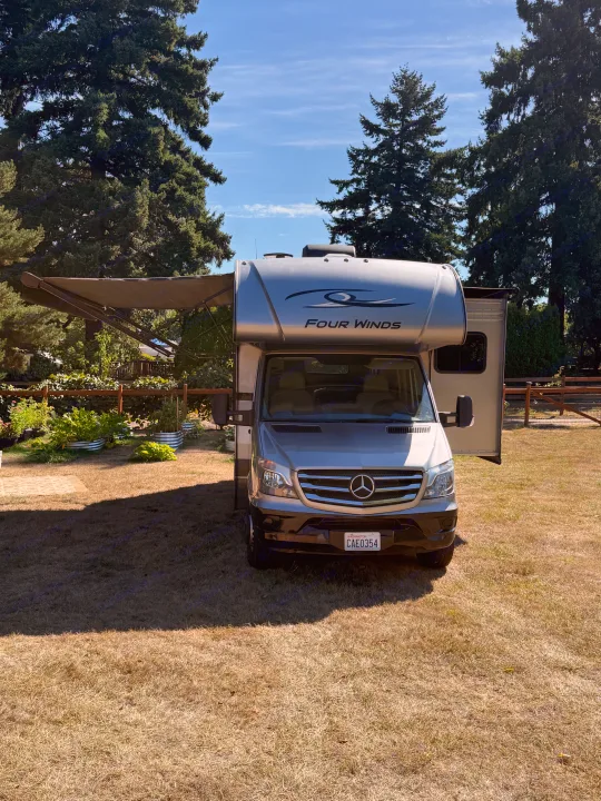 Spacious Mercedes-Benz Sprinter RV rental parked in a sunny yard with awning extended, ready for adventure.. Thor Four Winds 2019