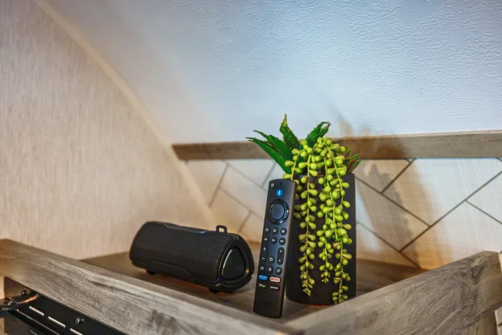 Cozy RV rental interior with entertainment essentials: A portable speaker, Fire TV remote, and decorative plant on a shelf.. Wayfinder Go Lite 2026