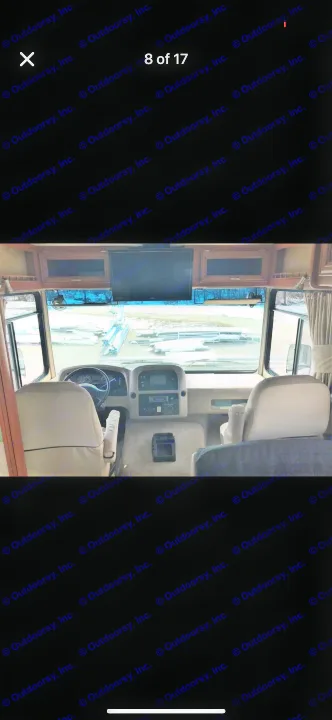 Interior view of an RV rental cockpit with dashboard, driver/passenger seats, and overhead TV.. Forest River Georgetown 320 DS 2011