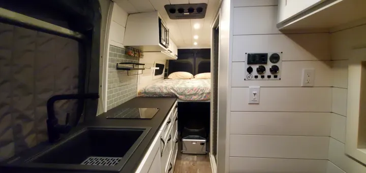 Experience compact living in this custom camper van interior, perfect for an rv rental adventure, featuring a kitchen and cozy bed.. Activan Cypress 170 2022
