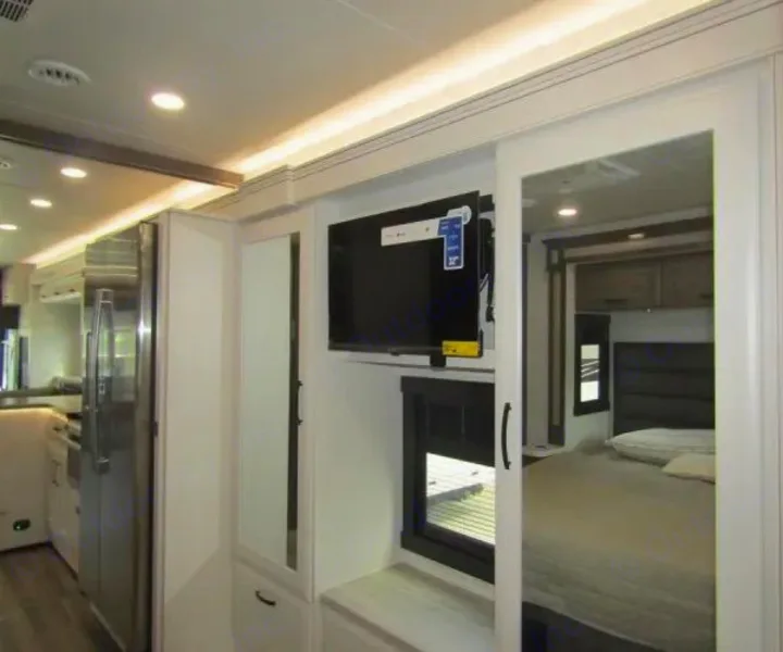This RV rental features a modern interior: kitchen, mounted TV, and a comfortable bedroom visible in the reflection.. Jayco Precept 2025